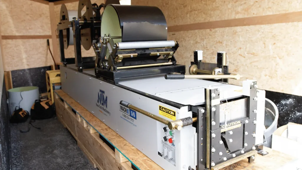Portable roll-forming machine producing a continuous seamless gutter from aluminum coil at a residential jobsite