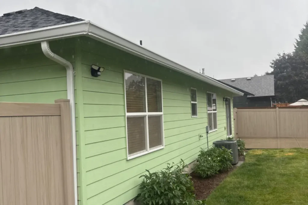Gutter Installation Scappoose 4 White 6K gutters and downspout installed on the back side of a light green home in Scappoose, Oregon.