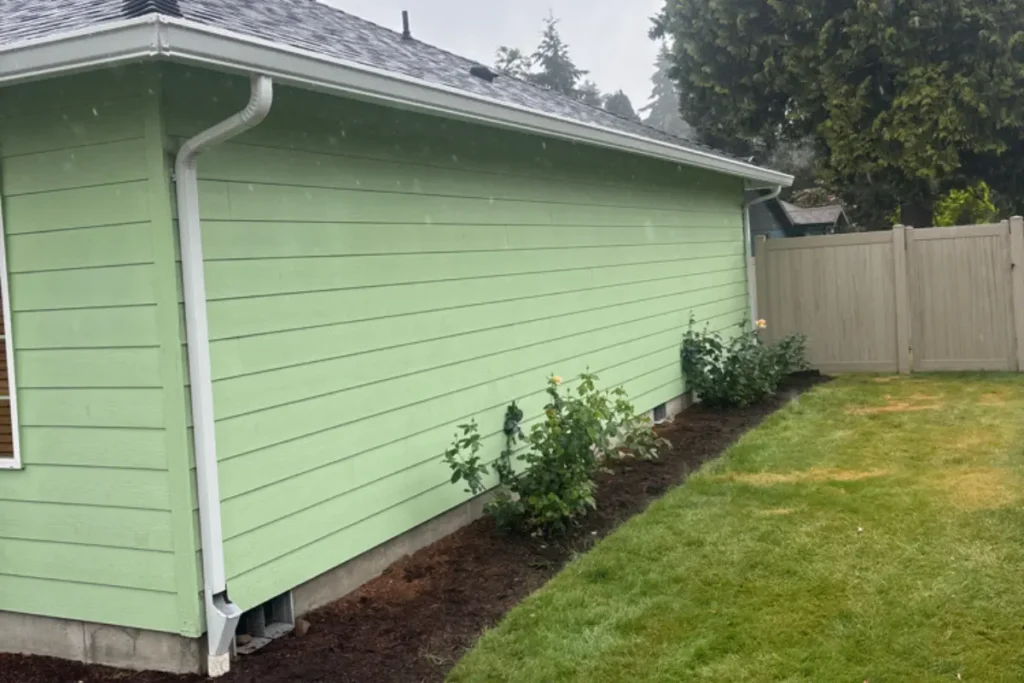 Gutter Installation Scappoose 6 White downspout and seamless gutter installed along the backyard side of a green home in 52287 SE Tyler St, Scappoose.