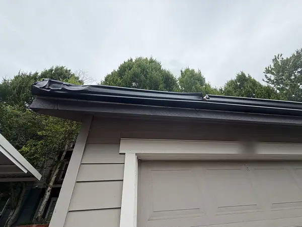 Close-up of a black seamless gutter along a townhome garage eave in Wilsonville