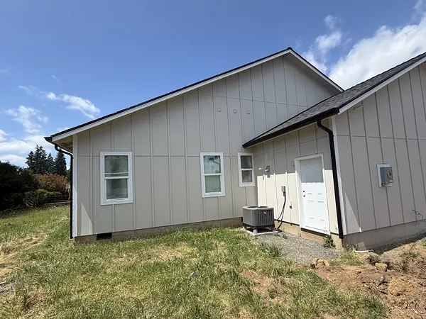 New-construction board-and-batten home with black gutters and black downspouts under a clear blue sky