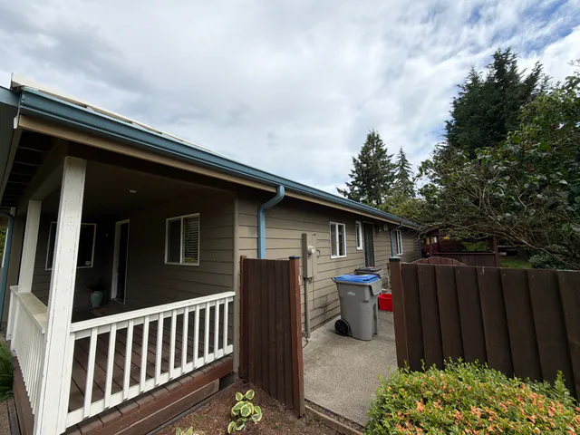 Blue gutter and downspout along the roof edge above a covered front porch with white railings