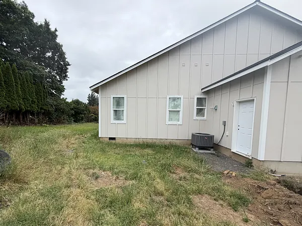 New white board-and-batten home in Scappoose with black seamless gutters and downspouts