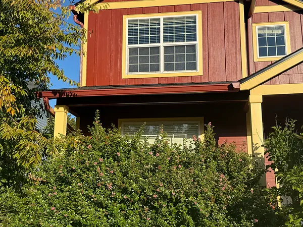 Dark red seamless gutter over a covered porch on a red and gold Scappoose home, matched to the siding trim