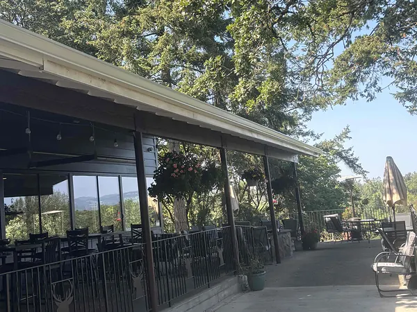 Long white seamless gutter along a commercial covered patio in St. Helens with outdoor seating and river-valley views