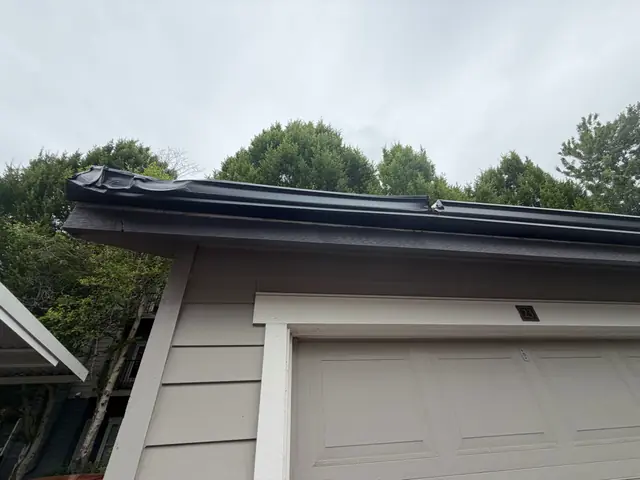 Crushed section of black gutter along a garage roof edge in Wilsonville