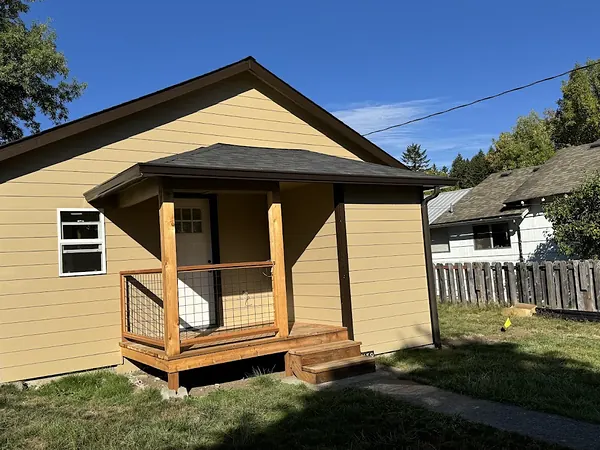 Yellow bungalow with dark gutters along the main roof and a new covered front porch with cedar posts