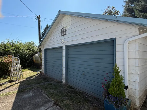 Detached double garage in Scappoose with blue doors and a new white seamless gutter and downspout