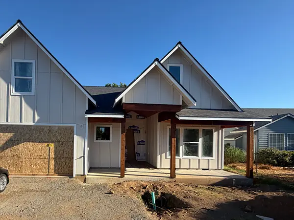 New-construction board-and-batten home in Scappoose with fresh gutters before the driveway is finished