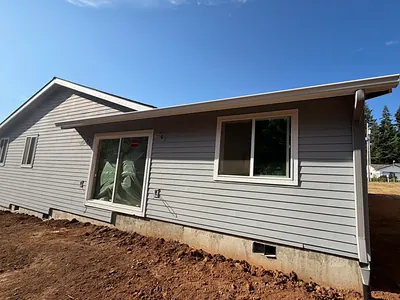 New white gutter and downspout on the corner of the remodeled Oregon City home above freshly graded soil
