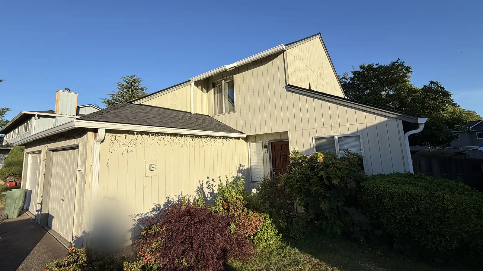 Two-story Hillsboro home with vertical siding and new white seamless gutters and downspouts in the evening sun