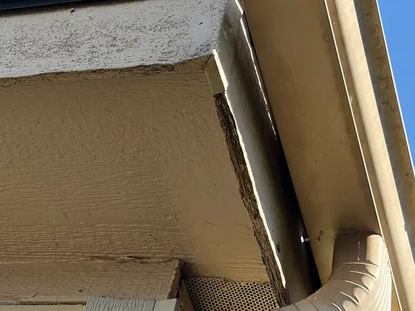 Close-up of an old tan gutter and downspout elbow pulling away from the fascia on a Scappoose home