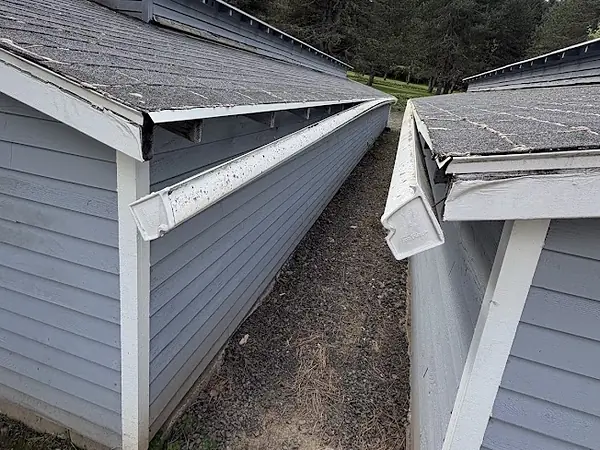 Two long gutter runs sagging and pulling away from the eaves of neighboring Oregon buildings