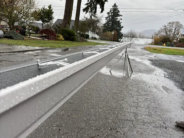 Freshly formed length of seamless aluminum gutter resting on stands in the street at an Oregon job site