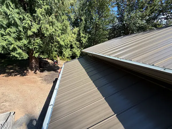 New seamless gutter on hidden hangers along the edge of a metal-roof shop in St. Helens