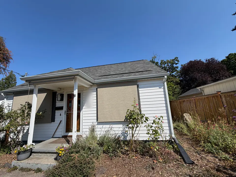 White Portland bungalow with new seamless gutters along the porch and main roof and a downspout at the front corner