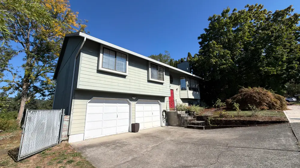 Two-story Troutdale home with a two-car garage, white seamless gutters and downspouts under a blue sky
