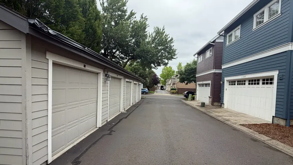 Row of townhome garages with dark seamless gutters along a quiet alley in Wilsonville, Oregon