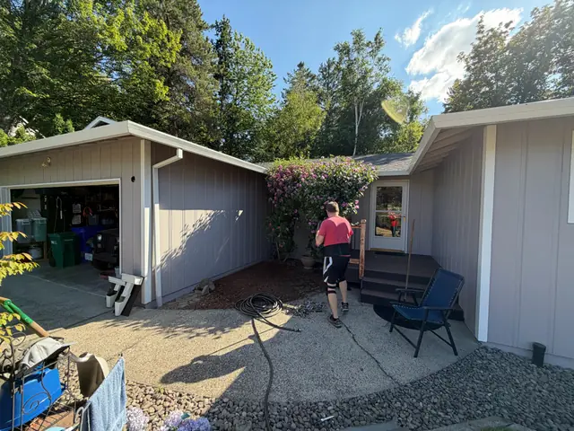 White gutter along a gray garage eave with a white downspout at the corner of a Gresham home