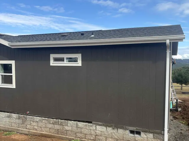 Dark gray home on a block foundation in Deer Island with a white gutter along the roof edge and a white downspout at the corner
