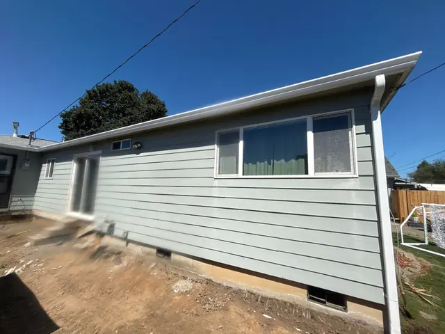 Light blue single-story home in St. Helens with a white gutter along the eave and a white downspout at the corner