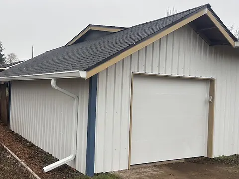 White seamless gutters and downspout on a detached Portland garage under an overcast winter sky