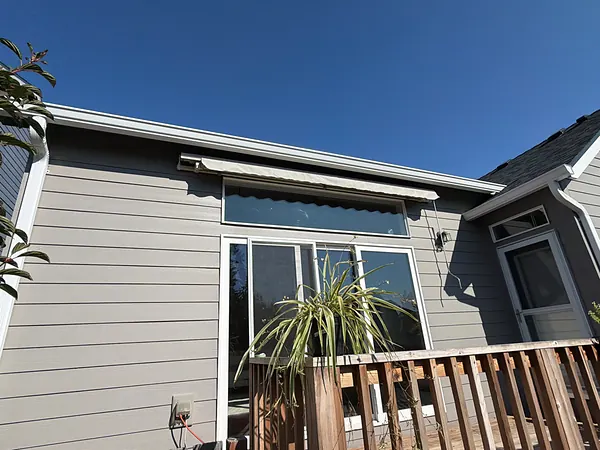 Back of a gray St. Helens home with white seamless gutters and downspouts above a sliding door and wood deck