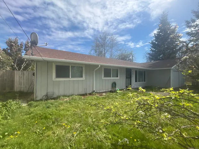Single-story ranch home in Tigard with white gutters along the eave and a white downspout, seen across a grassy yard