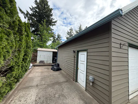 Brown garage with a white service door and a blue gutter along the eave in Tigard, Oregon