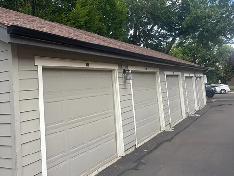 Seamless gutters running the full length of a row of townhome garages along a paved alley