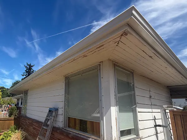 Weathered eave with peeling paint and an old gutter on a Portland home