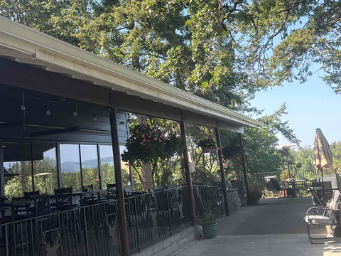 Long white gutter along a commercial covered patio with outdoor seating under oak trees