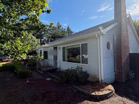 White vinyl ranch home with a brick chimney, white gutters and a downspout at the corner